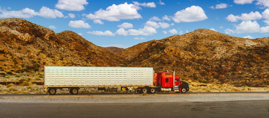 A tractor unit hauling a long dry van trailer on a desert highway
