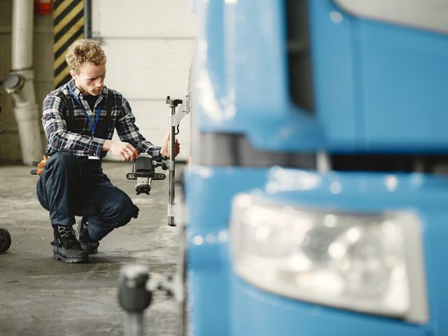 A technician setting up alignment gear against a heavy vehicle