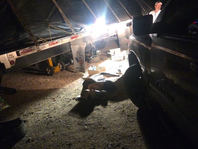 Working underneath a trailer at night under a work light at HTT Trailer Repair
